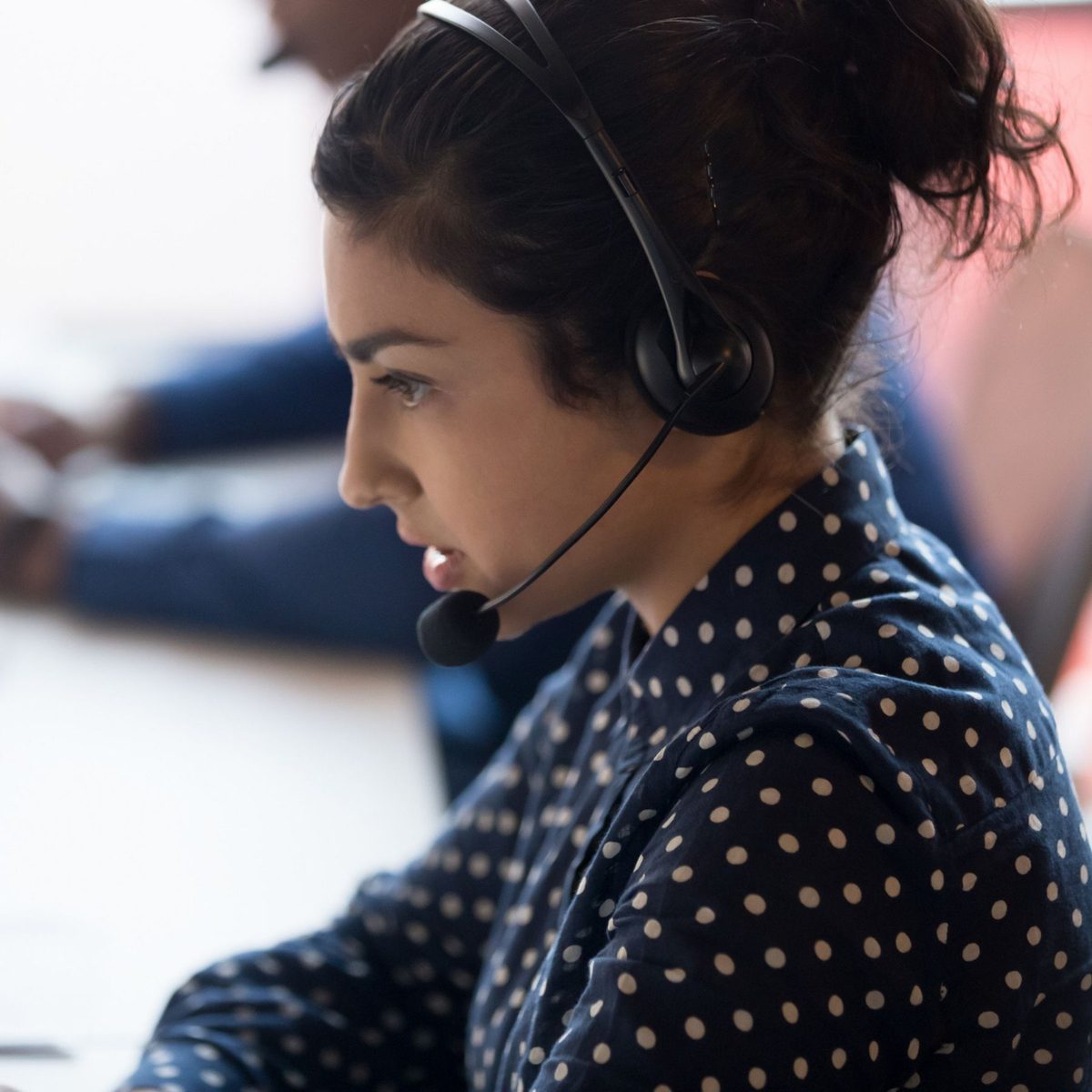 Woman wearing headset working in call centre, providing customer support.