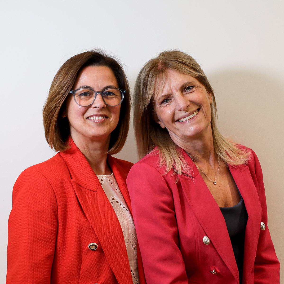 Two friendly receptionists, smiling warmly, inviting you to join our team