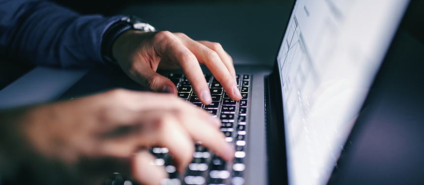Image of a man's hands working on a laptop depicting the notion of digital hostage taking and negotiation.