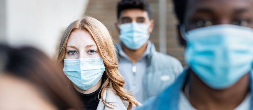 Image shows members of the public wearing masks and looking nervous, showcasing the measures taken during the Covid-19 pandemic to stay safe.